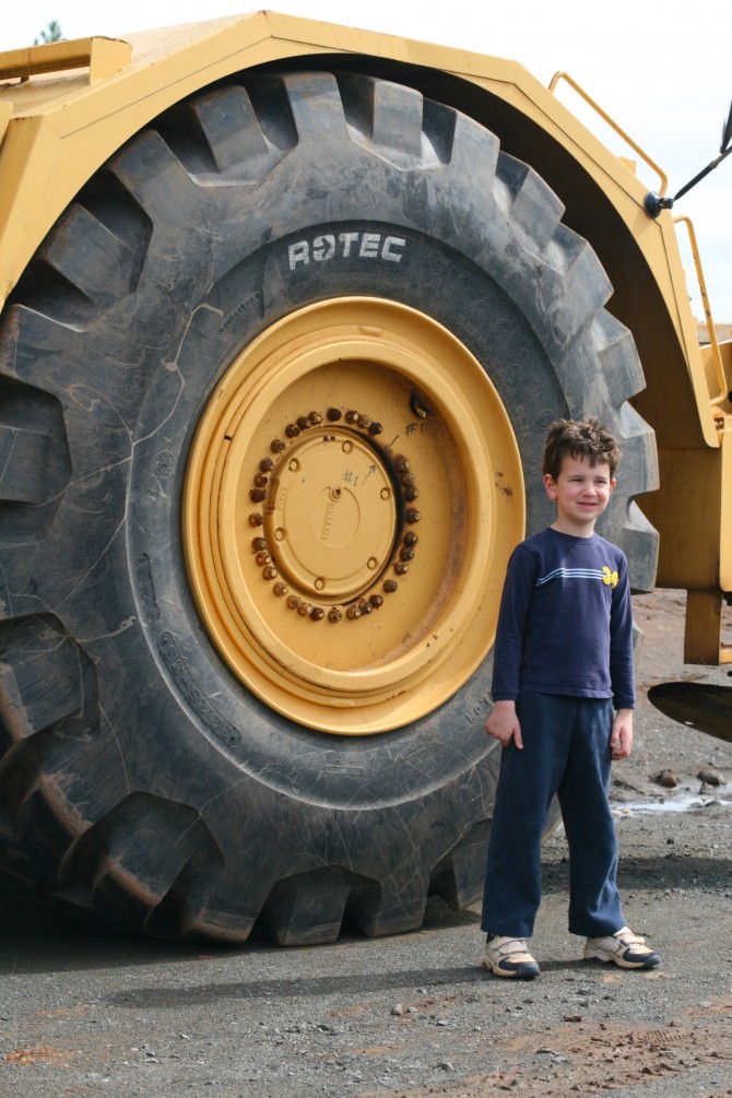 Ethan in front of the tire of a huge construction truck